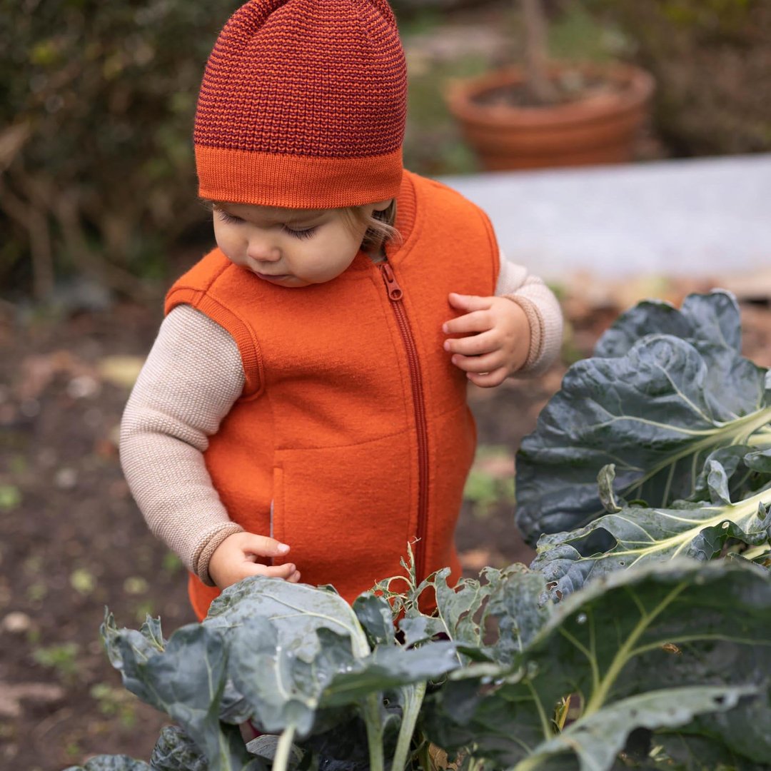 Toddler wearing Disana wool beanie hat in orange cassis melange