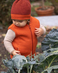 Toddler wearing Disana wool beanie hat in orange cassis melange