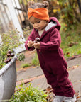 Lifestyle photo of toddler in Disana boiled wool overall in cassis