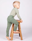 Boy climbing stool in Engel children's 100% organic wool leggings in sage heather