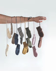 Set of Engel wool fleece baby mittens hanging from a woman's arm