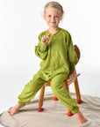 Child wearing Cosilana wool terry footless pajamas in green sitting on chair