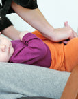 lifestyle photo of baby in Engel long sleeve bodysuit and tangerine baby leggings by Engel