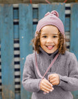 Girl wearing the Engel wool fleece hat with tassel in rose melange