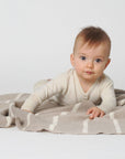 Lifestyle photo of our 100% wool baby blanket in sand with a natural stripe made by Reiff