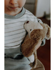 Young boy holding a Senger's organic cotton non-toxic floppy white beige small dog