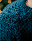 Close up of child in Disana Aran wool sweater in pacific color