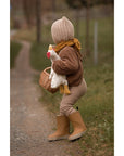 Child walking on a path in a bonnet carrying the Senger organic cotton non-toxic Cuddly white small chicken