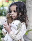 Young girl holding a Senger's organic cotton non-toxic floppy white beige small dog