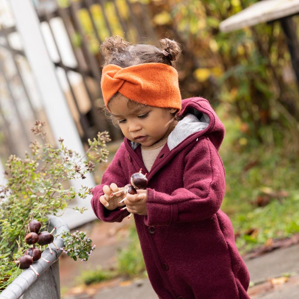 Lifestyle photo of toddler in orange wool Disana headband