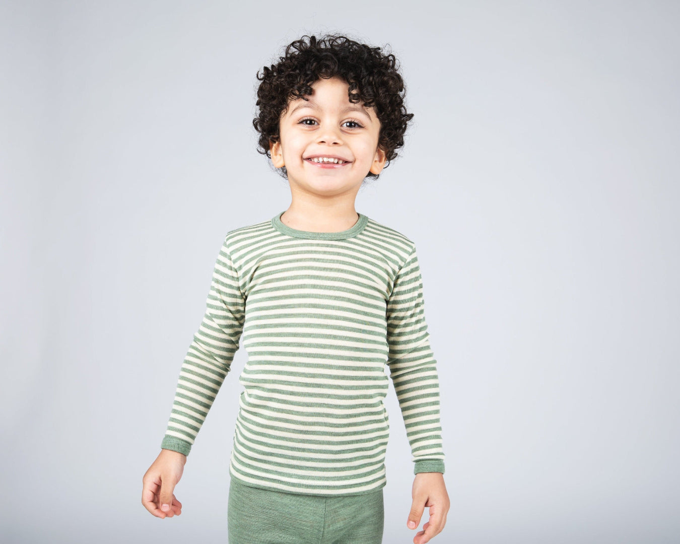 Boy in Engel kids thermal layer made of 100% wool in sage-natural stripe.