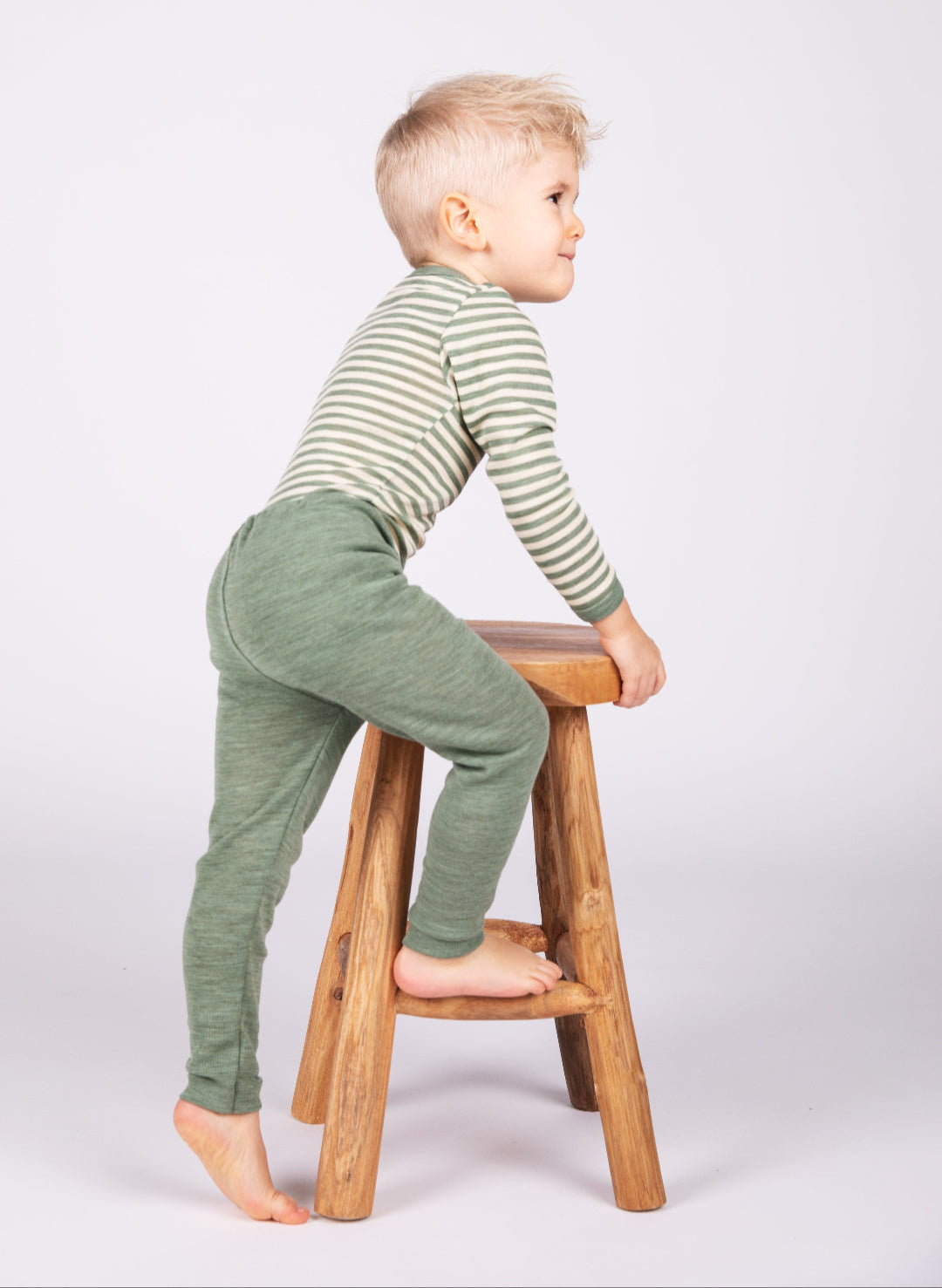 Boy climbing stool in Engel children&#39;s 100% organic wool leggings in sage heather
