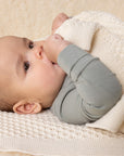 Lifestyle photo of a baby in Disana's organic merino wool honeycomb blanket in natural. 