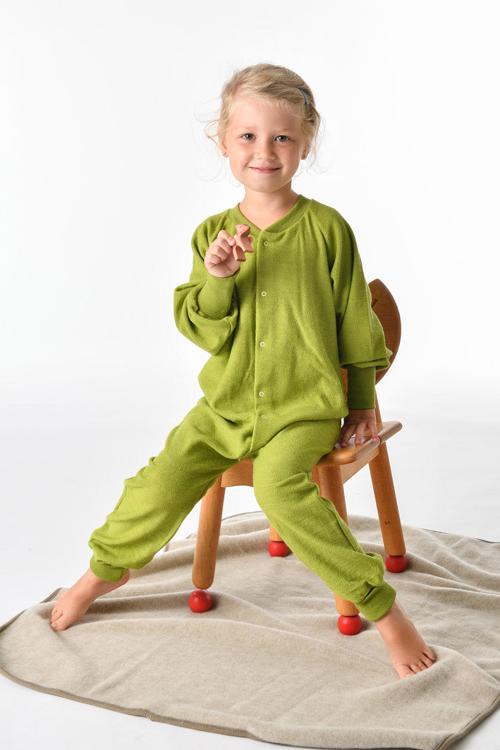 Child wearing Cosilana wool terry footless pajamas in green sitting on chair