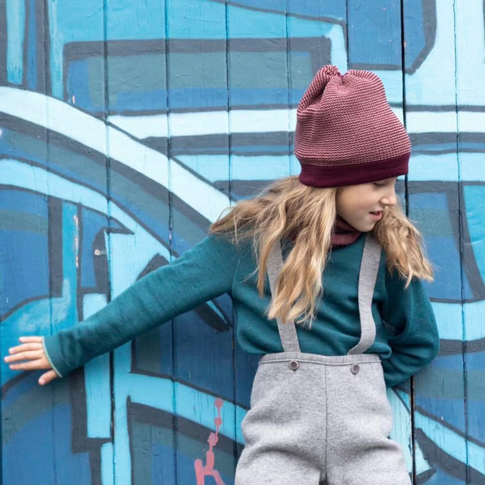 Lifestyle photo of girl in cassis rose wool beanie by Disana 