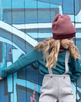 Lifestyle photo of girl in cassis rose wool beanie by Disana 