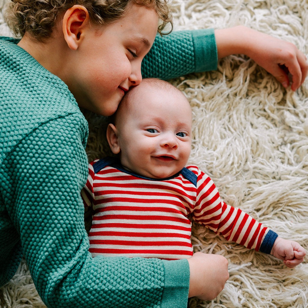 Lifestyle photo of Engel long-sleeved bodysuit of 100% wool in red and natural stripe