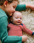 Lifestyle photo of Engel long-sleeved bodysuit of 100% wool in red and natural stripe