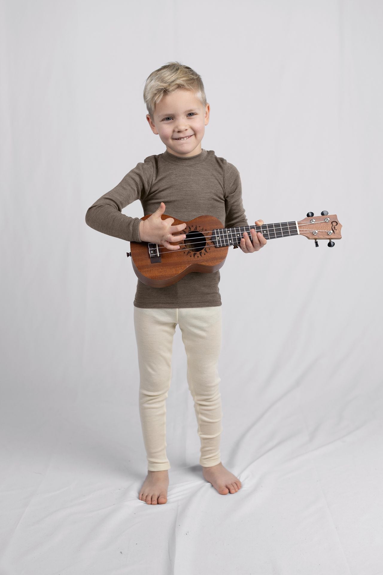 Boy playing ukulele in natural wool leggings