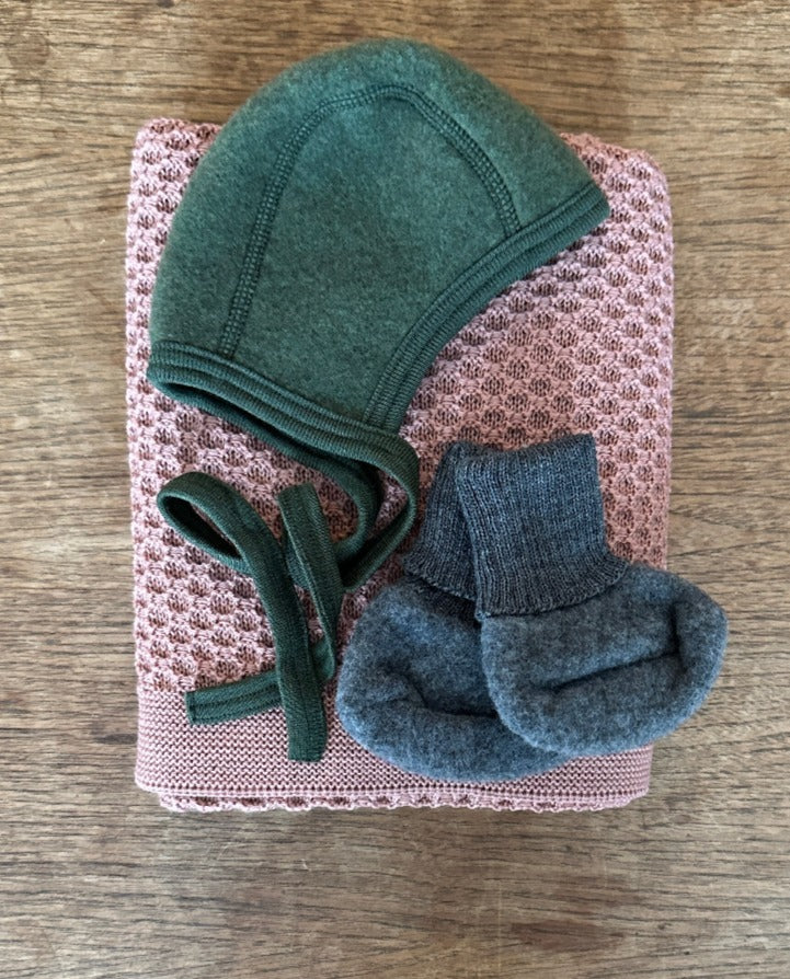 Disana honeycomb wool blanket in rose. Wool fleece  bonnet in green and wool fleece booties in charcoal. Both are by Engel 