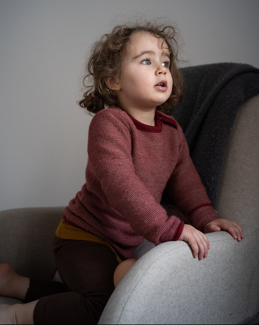 toddler in armchair wearing Disana melange sweater