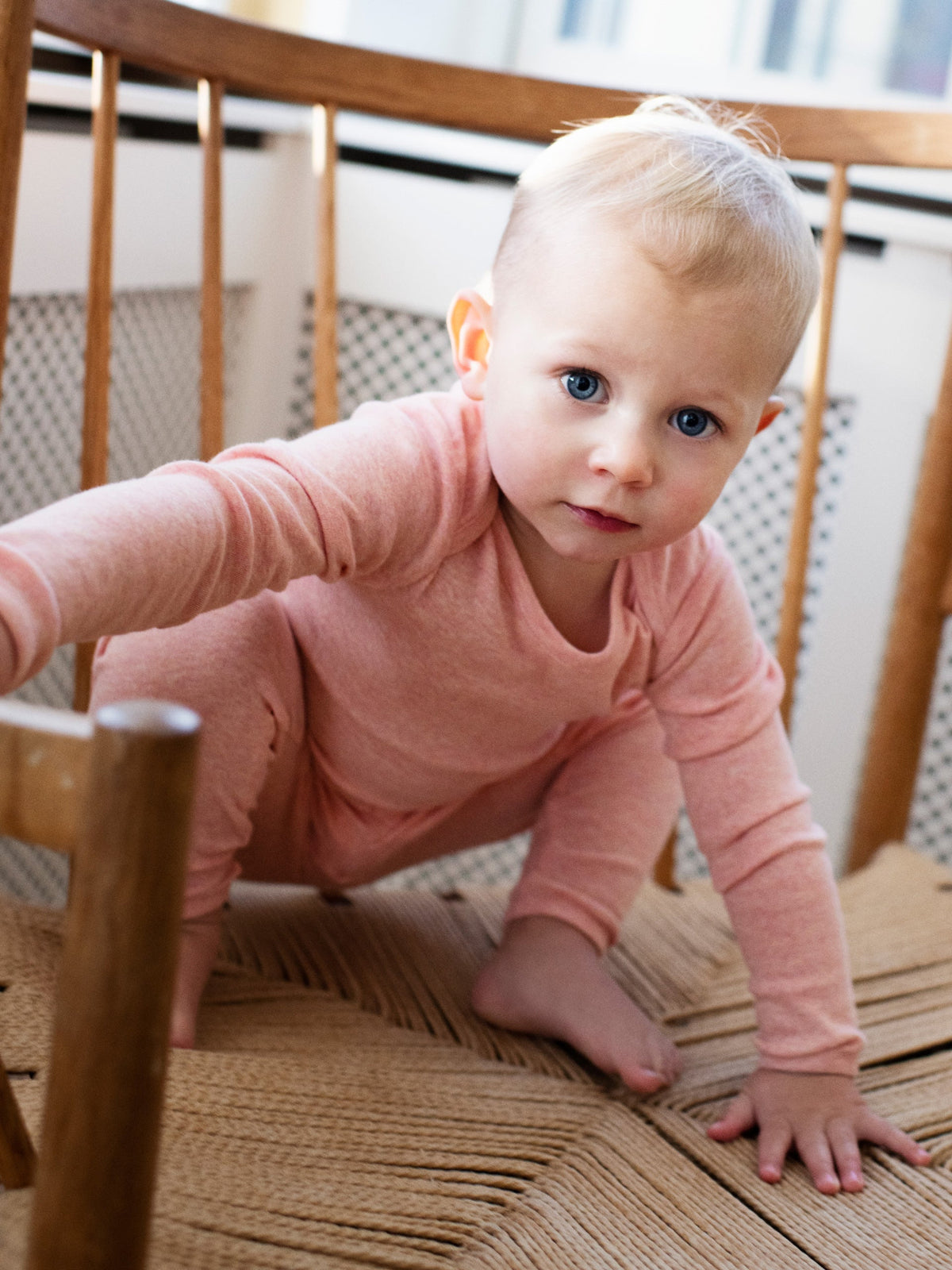 A baby on a chair wearing Serendipity's organic cotton coral bodysuit with matching baby leggings 