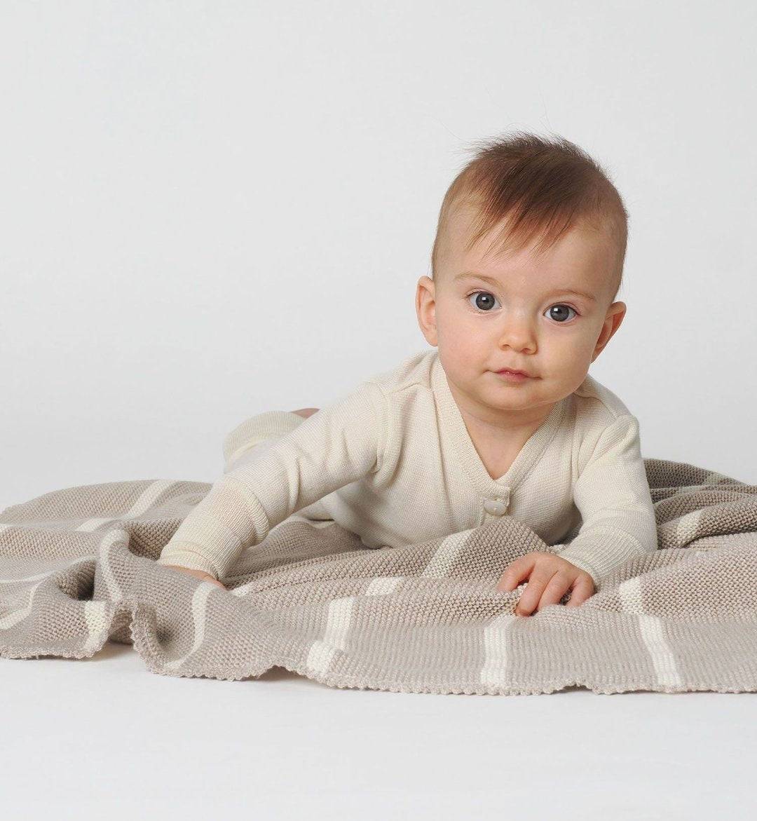 Lifestyle photo of our 100% wool baby blanket in sand with a natural stripe made by Reiff 