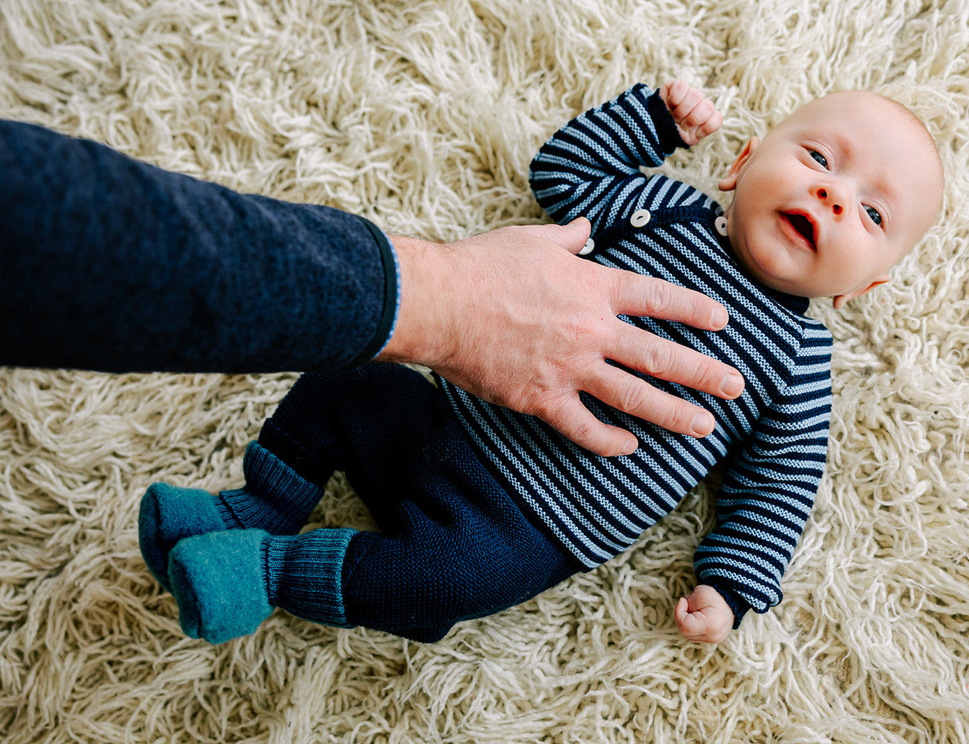 Lifestyle photo of baby in Reiff wool fleece booties, pants and side button cardigan