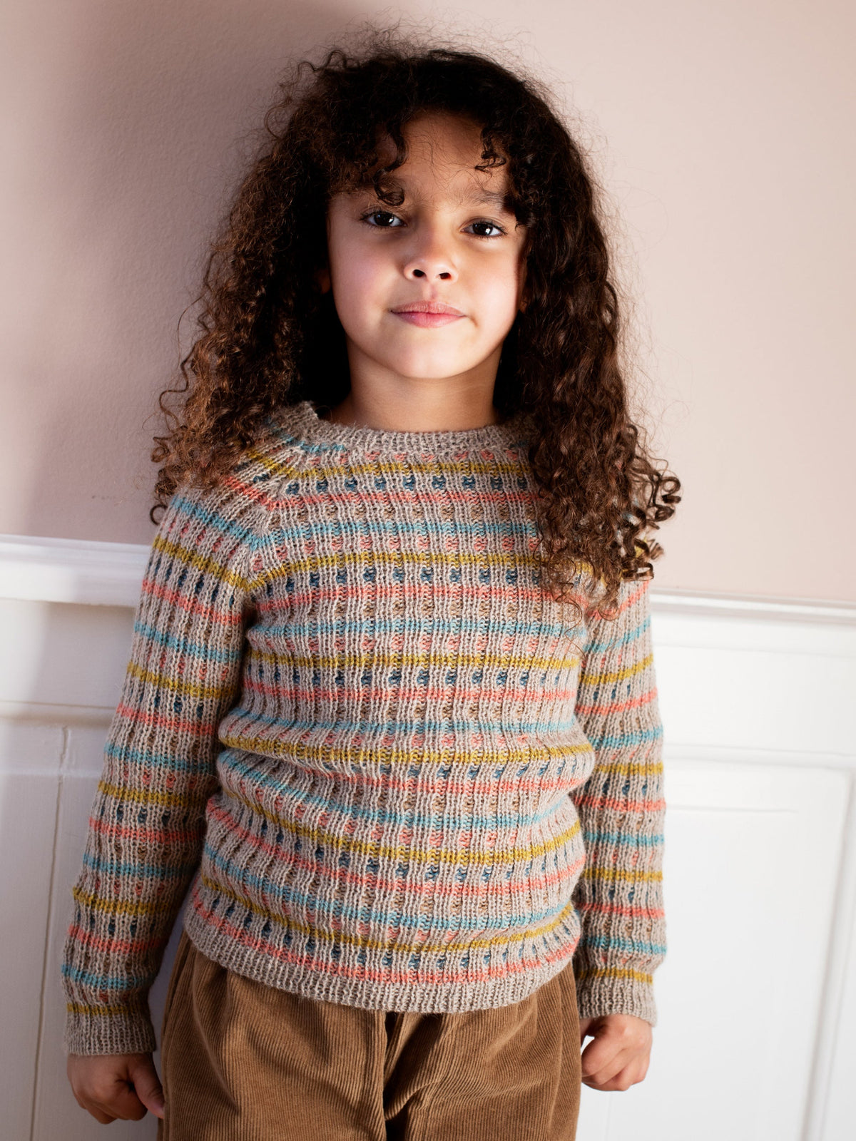 A young child wearing the multicolored striped rib alpaca sweater by Serendipity