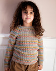 A young child wearing the multicolored striped rib alpaca sweater by Serendipity
