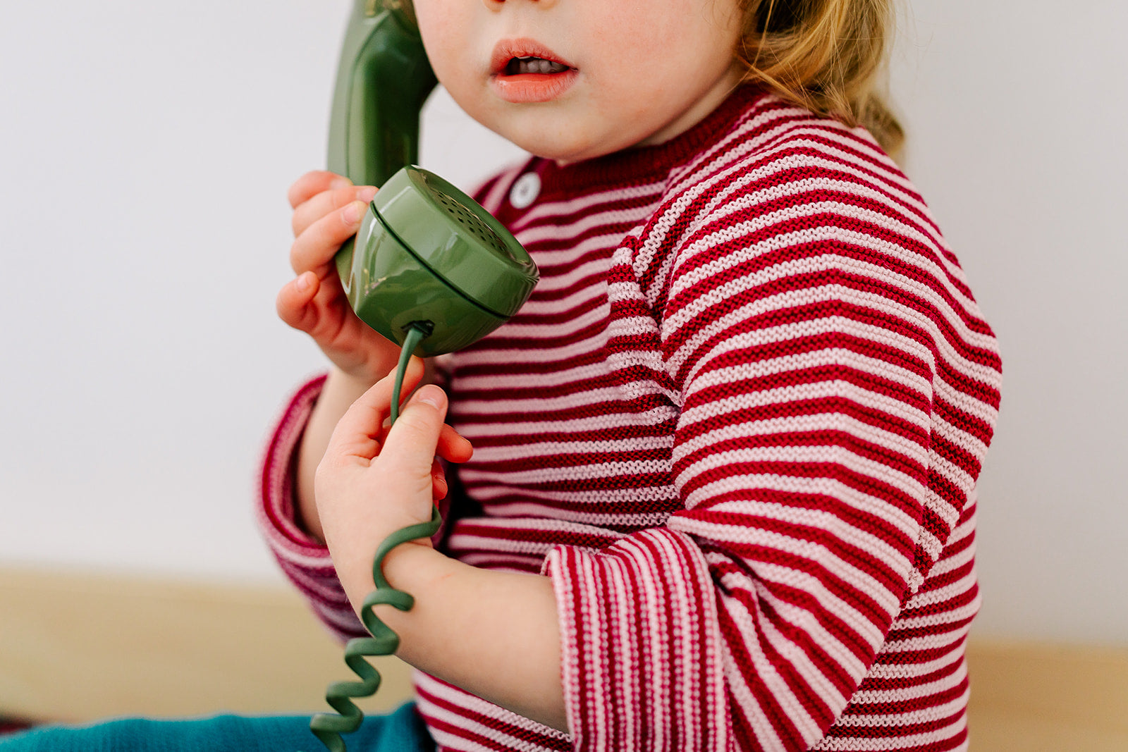 Child in berry-rose stripe 100% organic wool side button cardigan by Reiff
