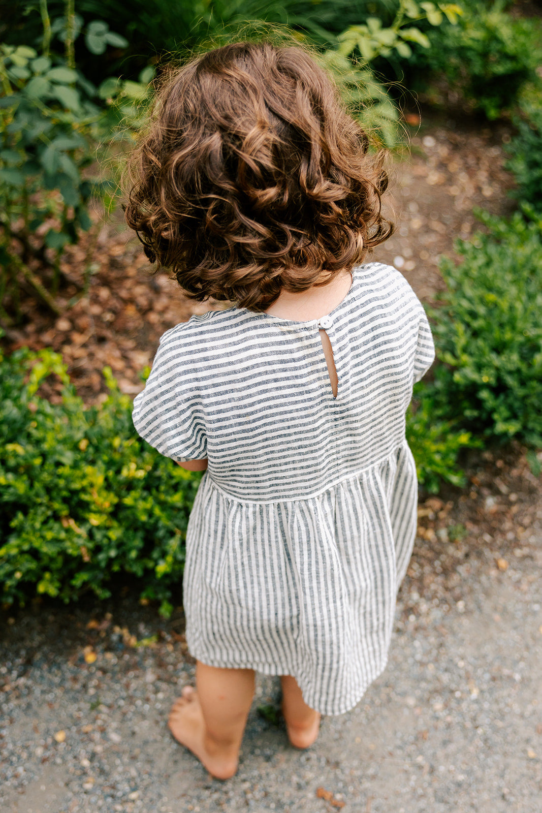 Girl in thin stripe linen summer dress by Bigelow Lane