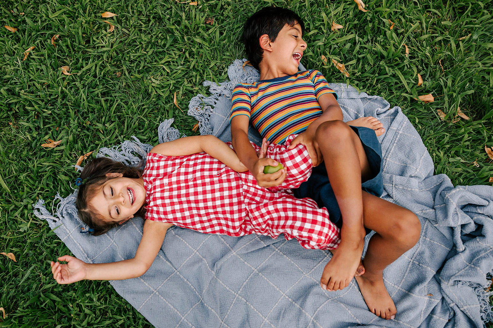 Girl lying in grass in a red Linenfox gingham linen jumpsuit