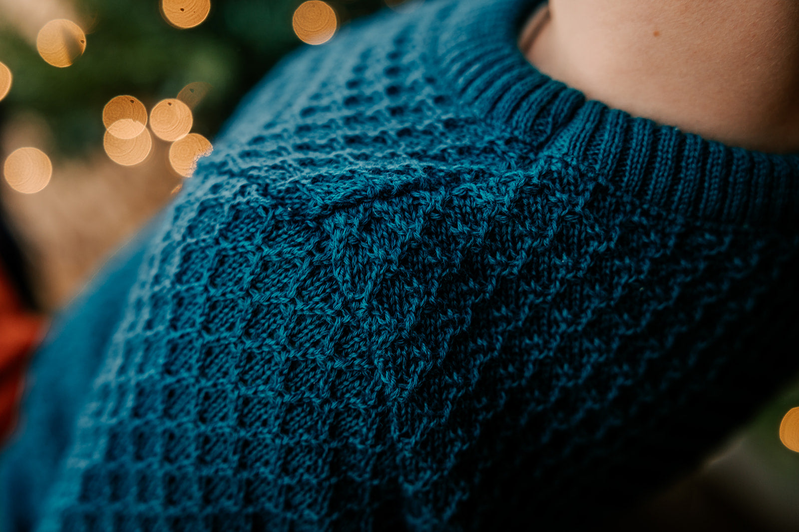 Close up of child in Disana Aran wool sweater in pacific color
