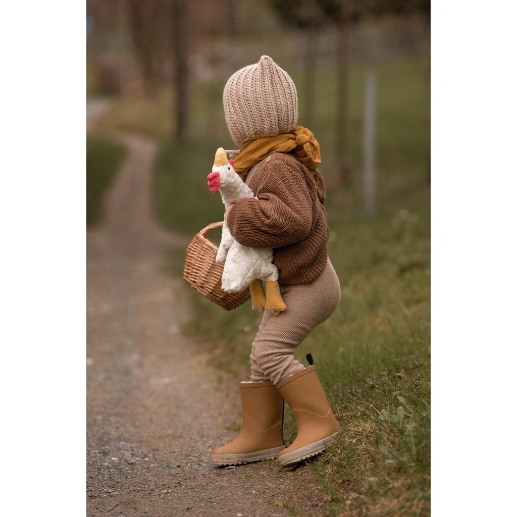 Child walking on a path in a bonnet carrying the Senger organic cotton non-toxic Cuddly white small chicken 