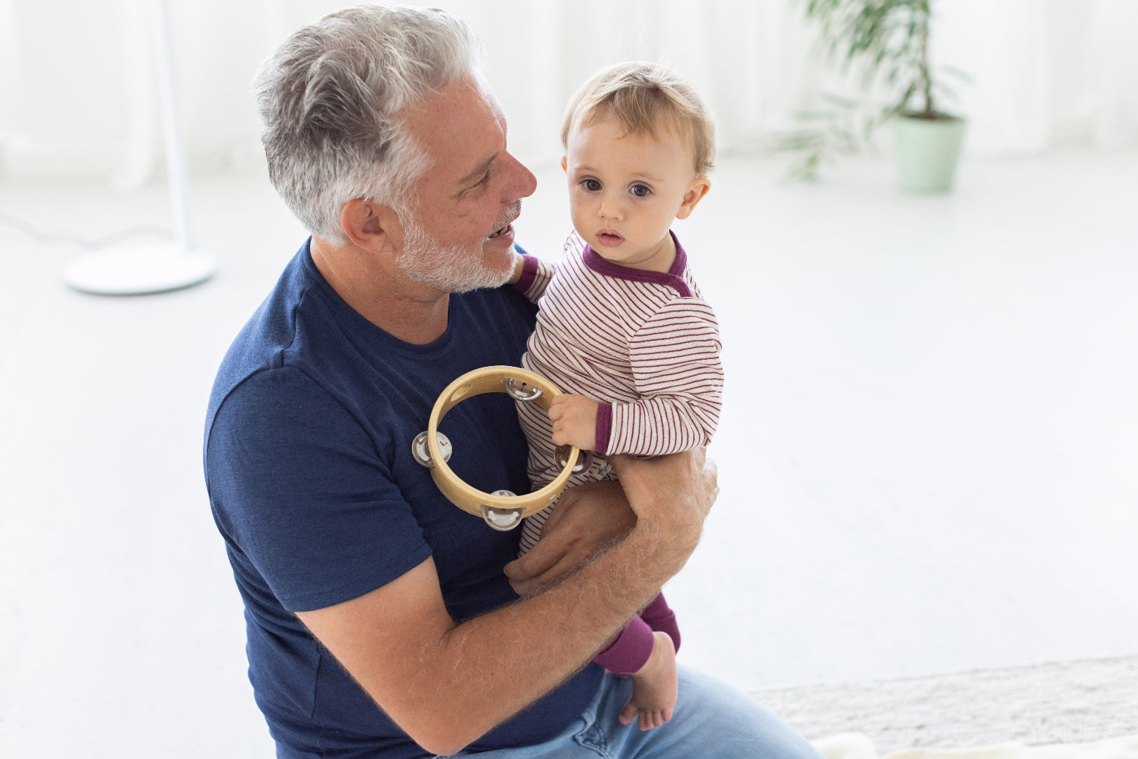 Father holding baby in Engel wool/silk thin stripe pajamas in orchid-natural