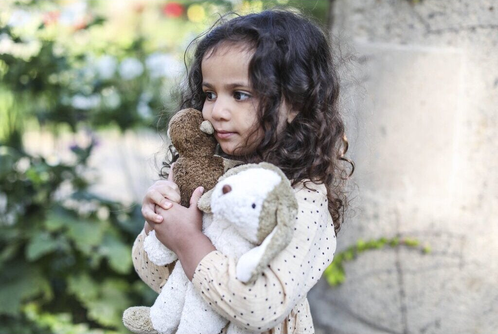 Young girl holding a Senger's organic cotton non-toxic floppy white beige small dog 